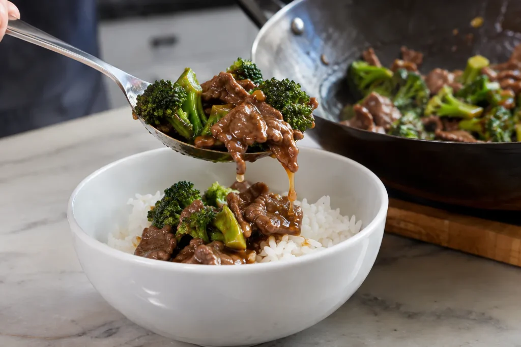 Beef and broccoli stir fry being spooned from a wok into a serving bowl