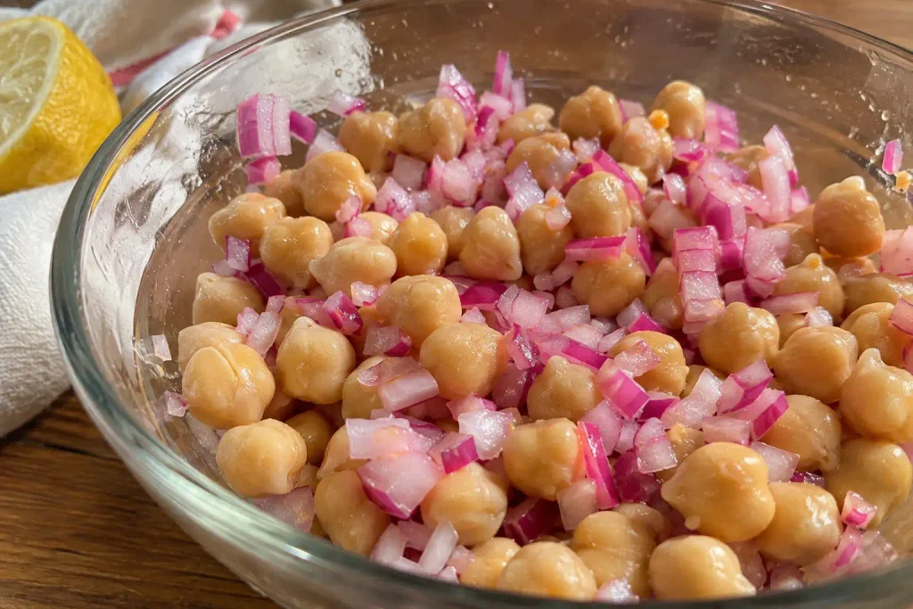 Chickpeas and diced red onion soaking in lemon juice for a Mediterranean chickpea salad