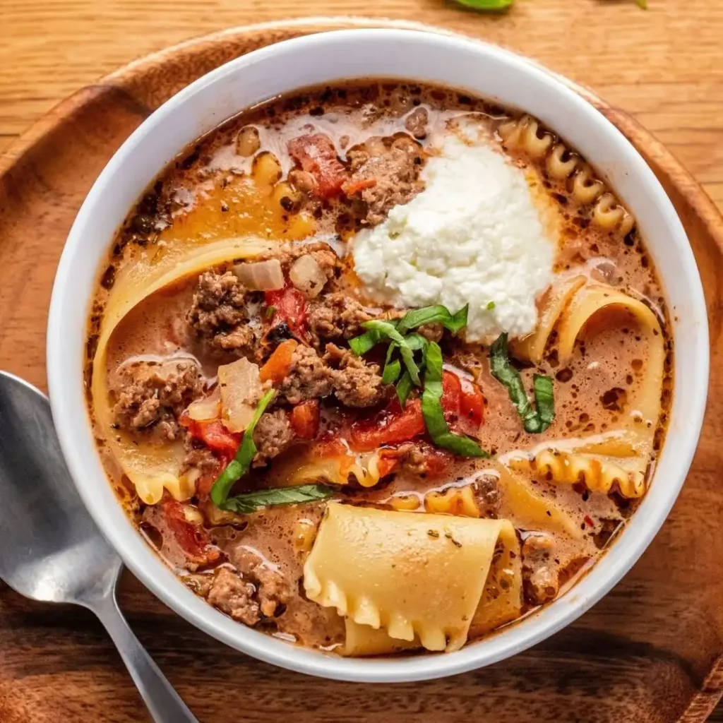 Lasagna Soup Recipe: A Hearty One Pot Dinner in 40 Minutes 2 Homemade lasagna soup with ground beef, tomatoes, lasagna noodles, ricotta cheese, and fresh basil in a white bowl.