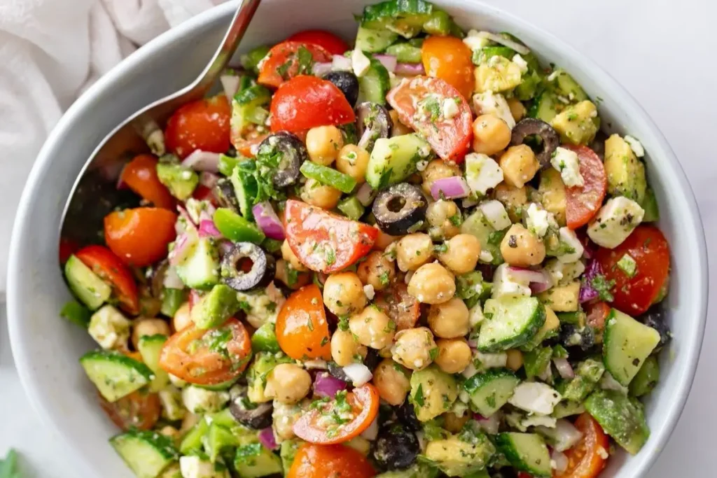 Fresh lemon herb chickpea salad with cucumber, cherry tomatoes, red onion, black olives, avocado