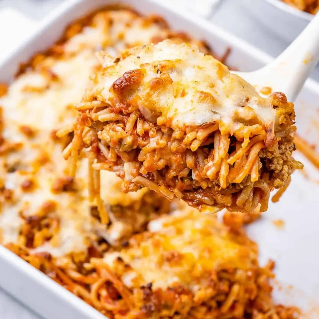 Cheesy scoop of million dollar spaghetti lifted from a baking dish