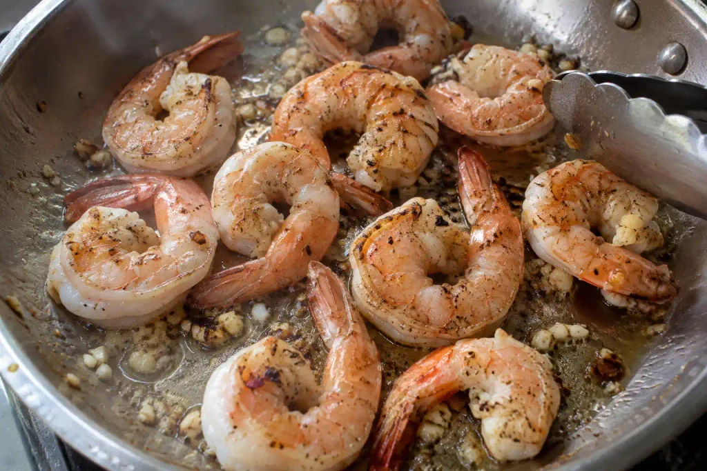 Shrimp Scampi Recipe: Juicy Shrimp and Linguine in 40 Minutes 4 Large shrimp curling into loose C shapes as they sear in a skillet for easy shrimp scampi